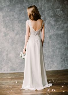 a woman in a white wedding dress standing on a wooden floor with flowers all around her