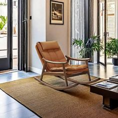 a living room with a rocking chair, coffee table and potted plants in it