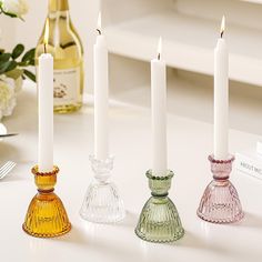 three candles are sitting next to each other on a table with wine bottles in the background