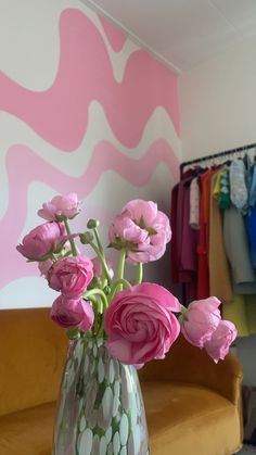 pink flowers are in a vase on a table next to a wall with an abstract design