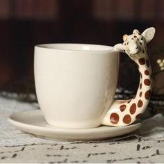 a giraffe figurine sitting on top of a white cup and saucer