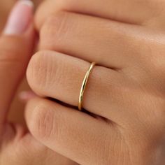 a woman's hand with a gold ring on her finger, holding it up