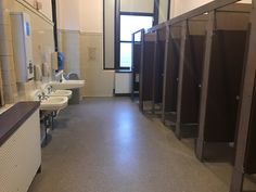 an empty public restroom with stalls and sinks