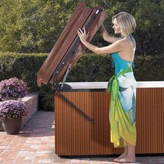 a woman in a colorful dress is holding an open suitcase on top of a wooden box