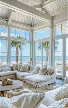 a living room filled with lots of furniture and large windows overlooking the beach in front of it