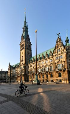 a person riding a bike in front of a large building with towers and spires