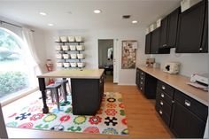 a kitchen with lots of counter space and black cabinetry, along with an area rug on the floor