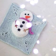 a crocheted snowman on top of a blue blanket with lights around it