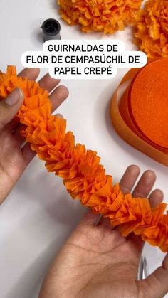 someone is making orange flowers out of paper crepe and then using scissors to cut them