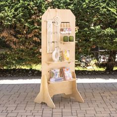 a wooden shelf with various items on it in front of some bushes and trees,