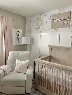 a baby's room with a white chair and floral wallpaper