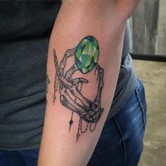 a man with a tattoo on his arm holding a green ball and scissors in one hand