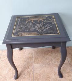 a small table with an animal design on it's top and bottom, against a blue wall