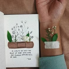 a hand holding an open book with a plant in it and a note attached to the cover