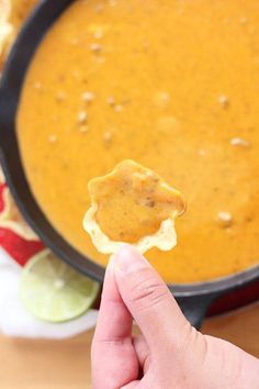 a hand holding a cracker over a bowl of soup