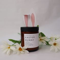 a candle with bunny ears sitting next to some flowers