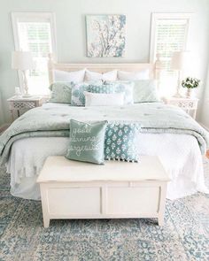 a white bed with blue and green pillows