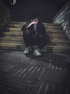 a man sitting on some steps with his hands to his face while looking at the camera