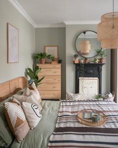 a bed room with a neatly made bed next to a dresser and mirror on the wall