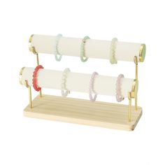 three pairs of bracelets are hanging on a wooden stand with two rings attached to them