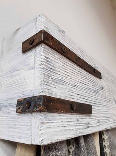 an old wooden box is hanging on the wall with two metal brackets attached to it