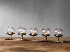 four glass candles are sitting on a metal stand