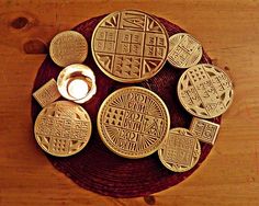 some gold colored cookies sitting on top of a wooden table next to a lit candle