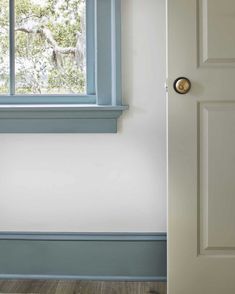 an empty room with a door and window on the wall, painted in pale blue