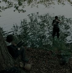 two people sitting on the bank of a lake