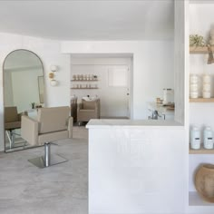 a living room filled with furniture next to a white kitchen and dining room table in front of a mirror