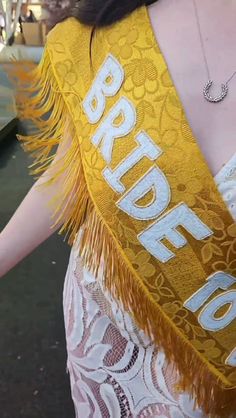 a woman wearing a yellow sash with white letters on it