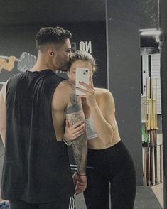 a man and woman standing in front of a mirror taking a selfie with their cell phone