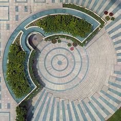 an aerial view of a circular garden with benches and trees in the center, surrounded by stone pavers