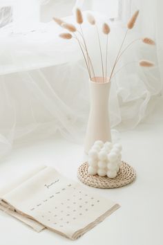 a vase with some flowers in it next to a notepad and napkins on a table