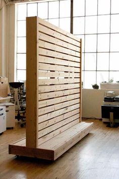 a wooden partition in the middle of a room with lots of windows and wood flooring