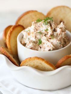 a white bowl filled with food sitting on top of a table next to crackers