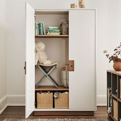 an open bookcase with baskets and a stuffed animal in the corner next to it