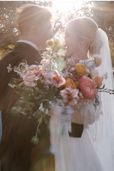 the bride and groom are kissing in front of the sun shining through the trees on their wedding day