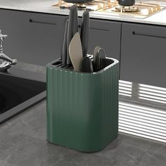 a green kitchen caddy with utensils and knives in it next to an oven