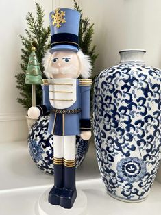 a blue and white nutcracker next to a vase