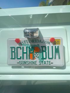 the license plate is on the back of a white truck with an orange and green emblem