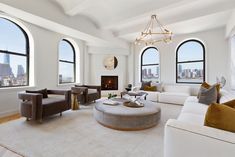 a living room filled with lots of furniture next to two large windows and a fire place