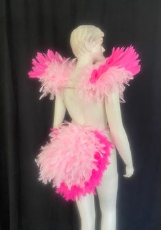 a mannequin with pink feathers on it's head and chest, standing in front of a black background