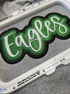 a close up of an embroidered patch on a gray shirt with the word eagles in white and green