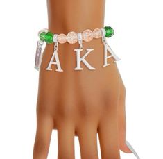 a woman's hand wearing a bracelet with the letters aka and flowers on it