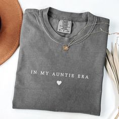 a gray shirt with the words in my anette era on it and a hat next to it