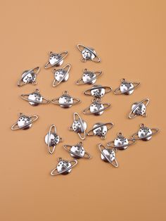 a bunch of silver charms sitting on top of a brown table next to each other