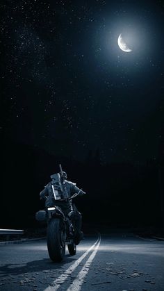 a motorcycle parked on the side of a road under a crescent moon and star filled sky