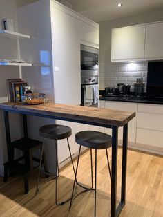 two stools sit at the end of a kitchen table in front of an oven