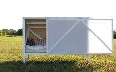 a dog bed made out of an old crate in the grass with its door open